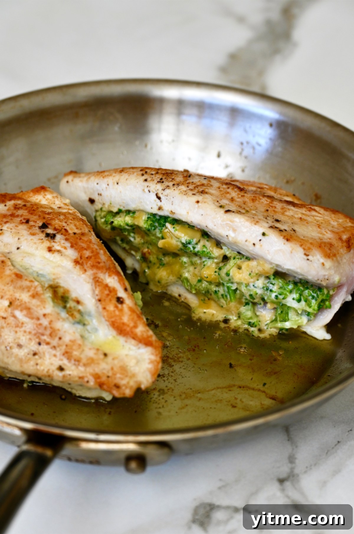 Seared stuffed chicken breast in a hot skillet.