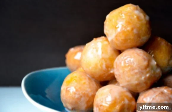 No-Fuss Yeast-Free Breads: Quick & Simple Recipes 7 A blue bowl containing homemade glazed doughnut holes stacked on top of each other, a delightful treat made without yeast