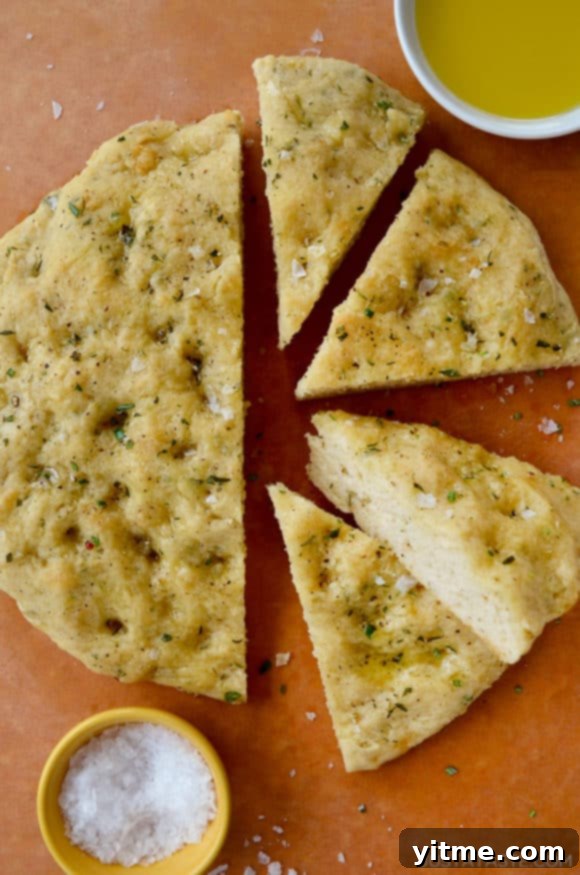 Four slices of Easy Homemade Focaccia (No Yeast) next to small bowls containing kosher salt and olive oil