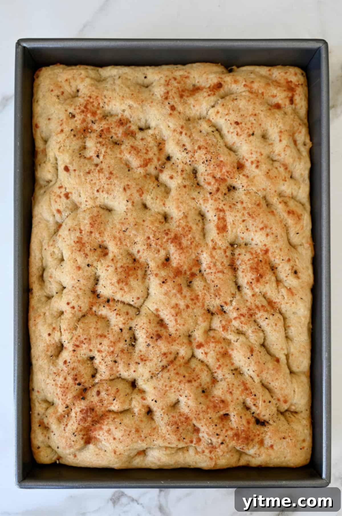 Freshly baked homemade focaccia topped with black pepper and Parmesan cheese.