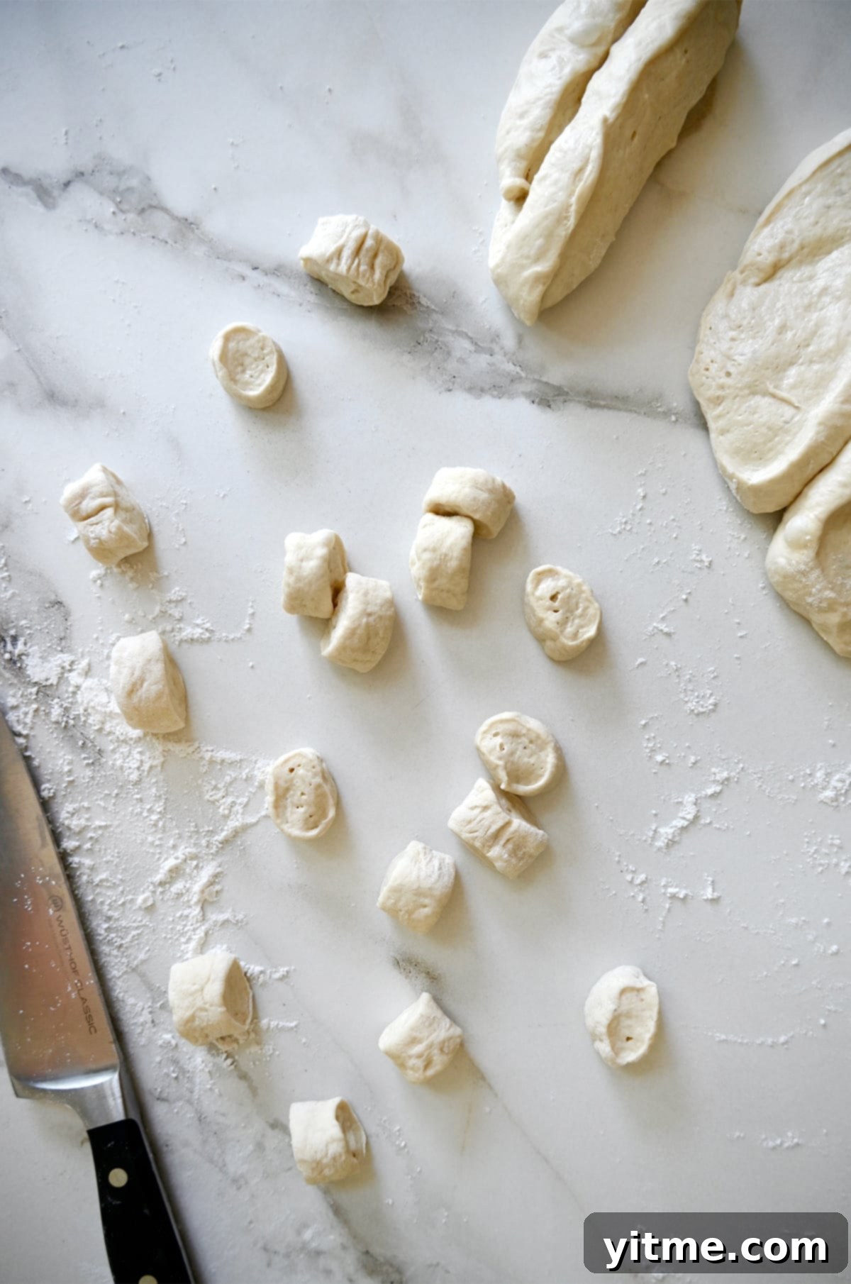 Fresh pizza dough meticulously cut into small, uniform pieces on a floured surface, ready for the next step in making soft pretzel bites.