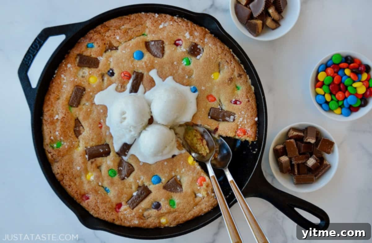 Spoons digging in to Halloween Candy Skillet Cookie topped with vanilla ice cream.