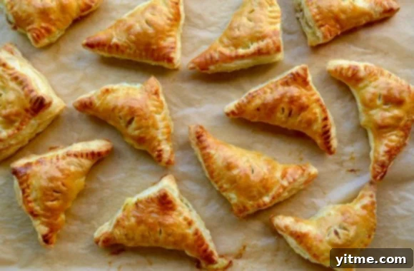 Freshly baked mini fruit and cheese turnovers on parchment paper