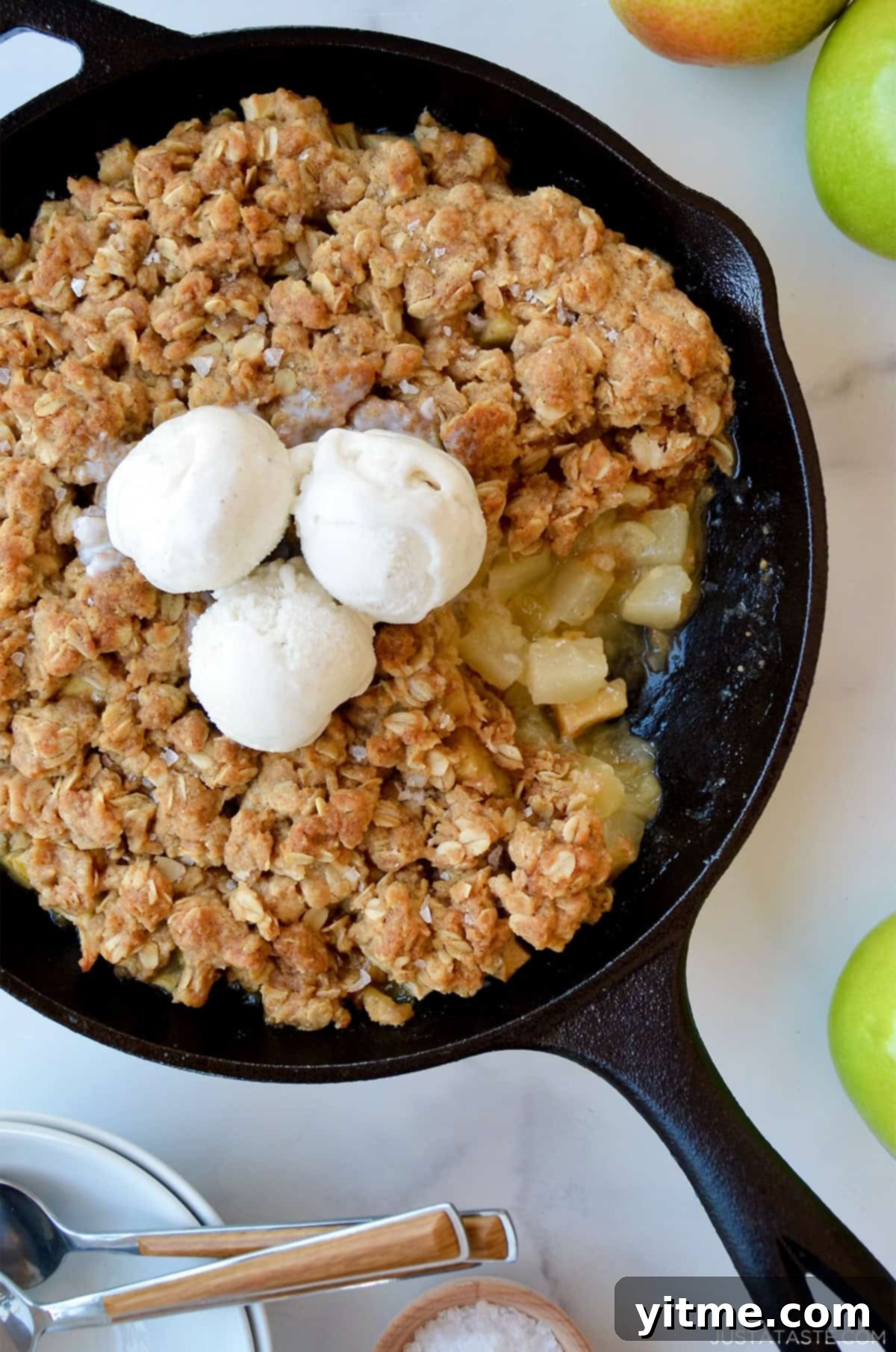 Apple pear crisp topped with three scoops of vanilla ice cream.