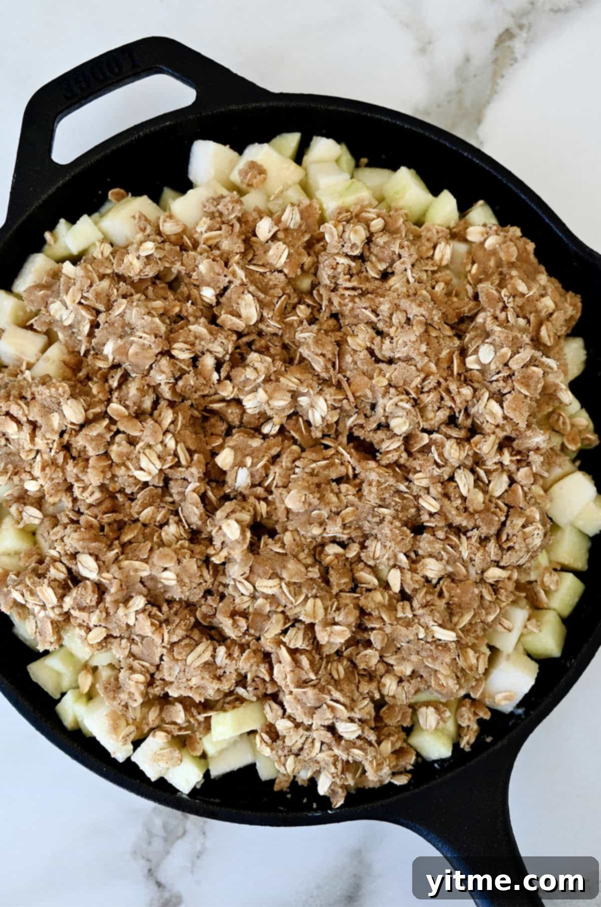 Unbaked apple pear crisp in a cast iron skillet.