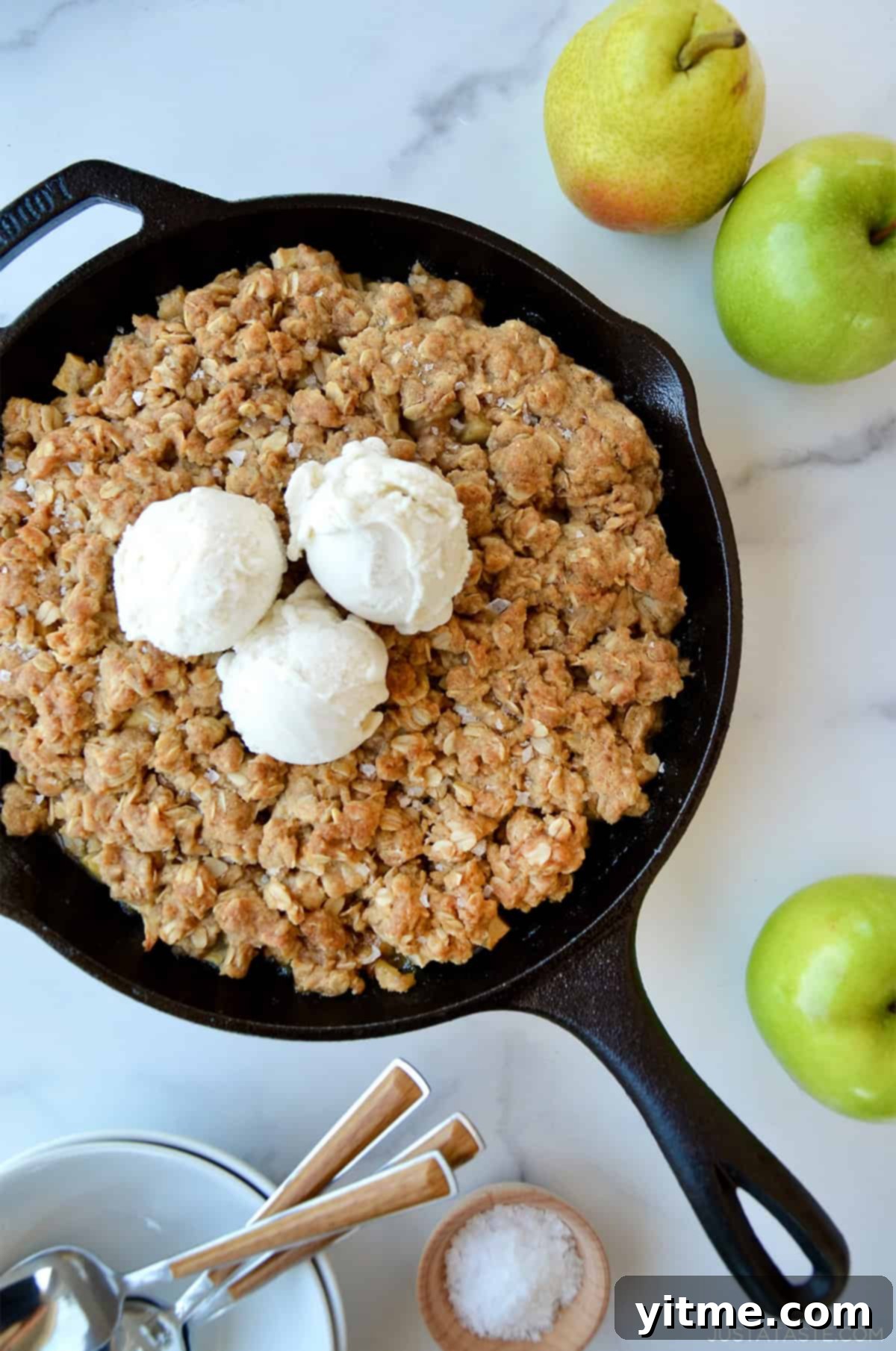 Apple pear crisp topped with a cinnamon-oat topping in a cast iron skillet.