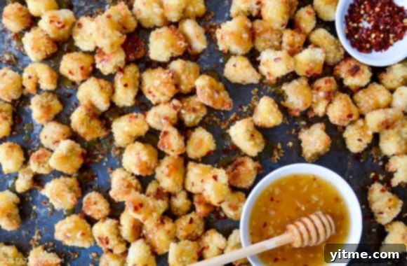 Easy baked popcorn chicken served next to a small ramekin filled with the tempting honey-garlic glaze
