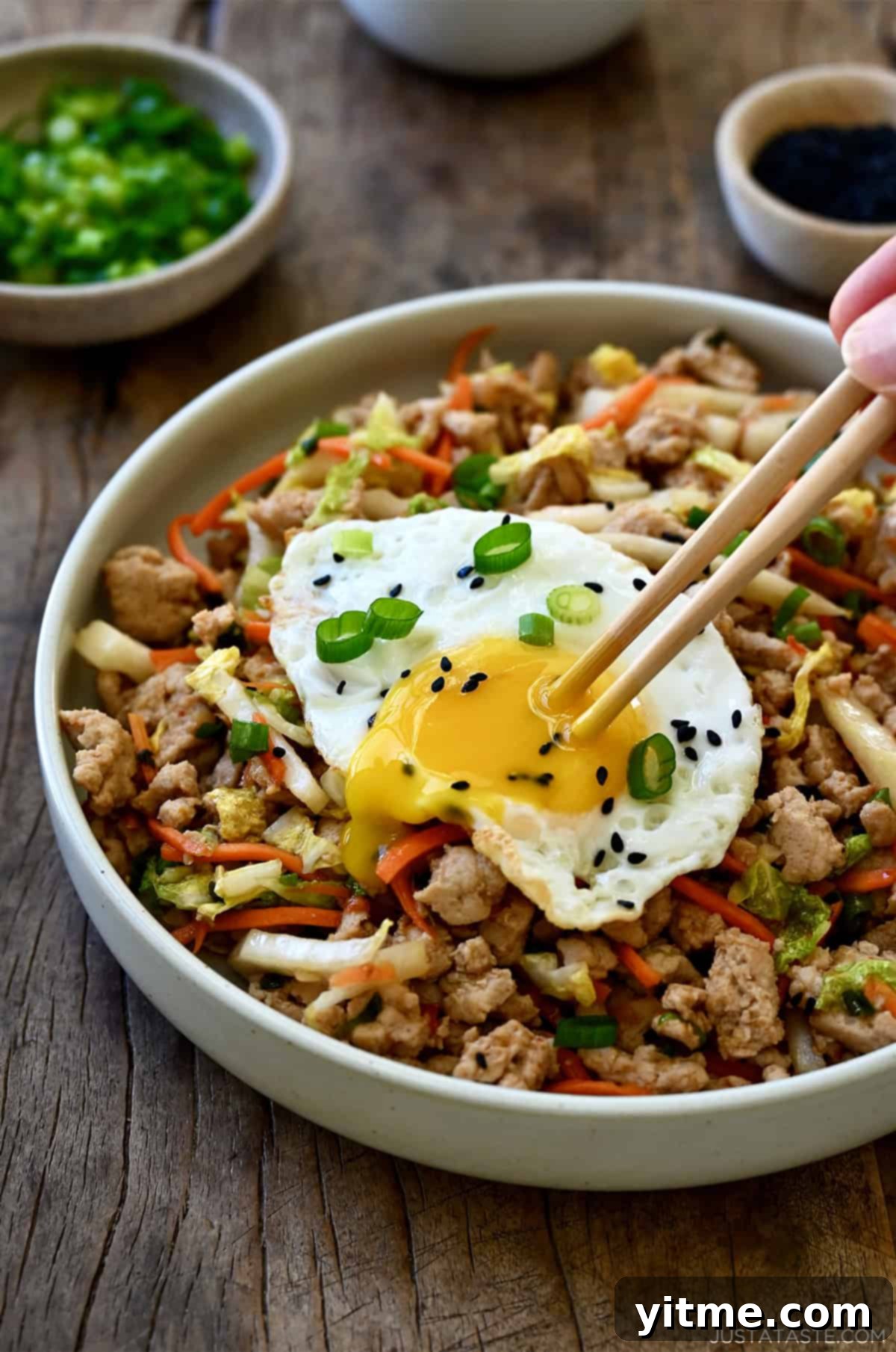 Egg roll bowl topped with a fried egg with runny yolk.