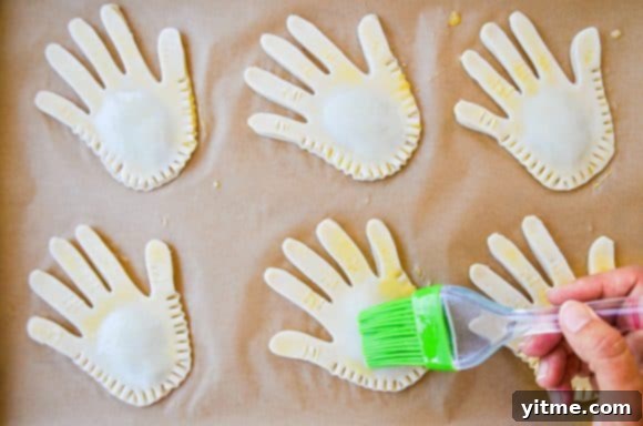 Hand applying egg wash to pie dough