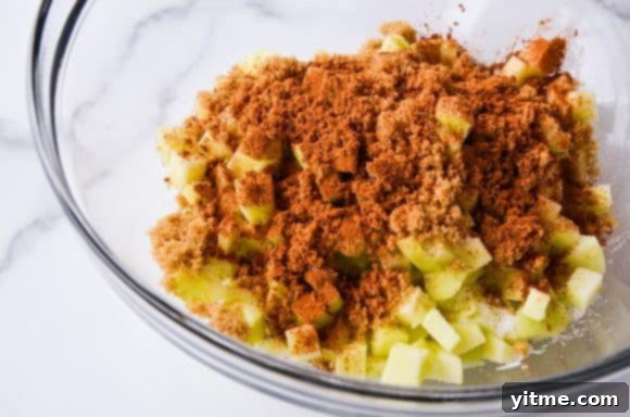 Clear bowl containing diced apples and cinnamon