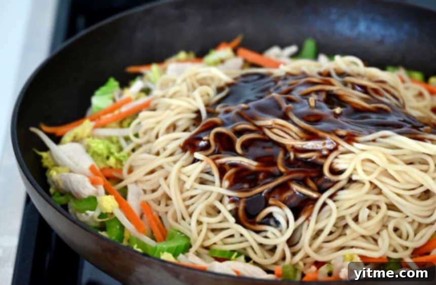 Chow mein sauce over noodles and veggies in a large skillet