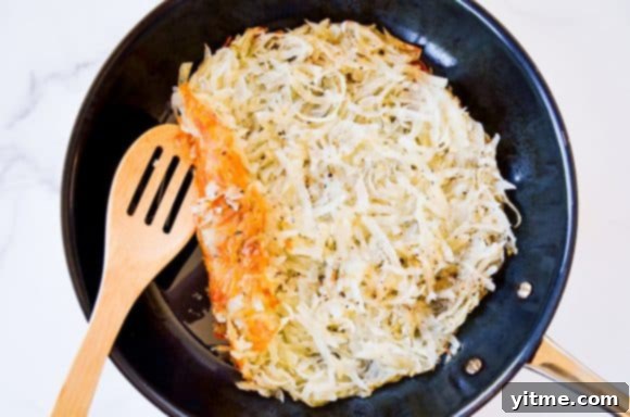 Crispy hash browns cooking in a large skillet