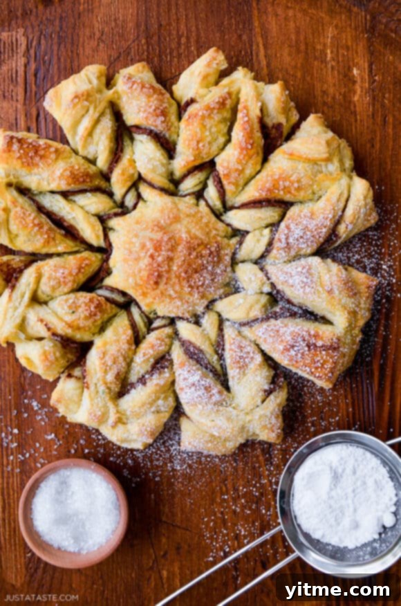 Effortless Snowflake Pastry Delight 2 A golden brown puff pastry snowflake dusted with powdered sugar, showcasing its intricate design.
