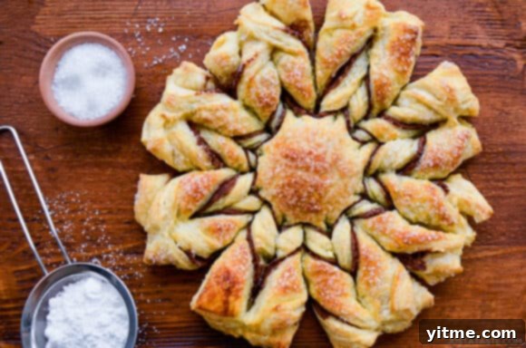 Effortless Snowflake Pastry Delight 9 An overhead shot of a perfectly baked puff pastry snowflake dusted with powdered sugar, emphasizing its festive appearance.