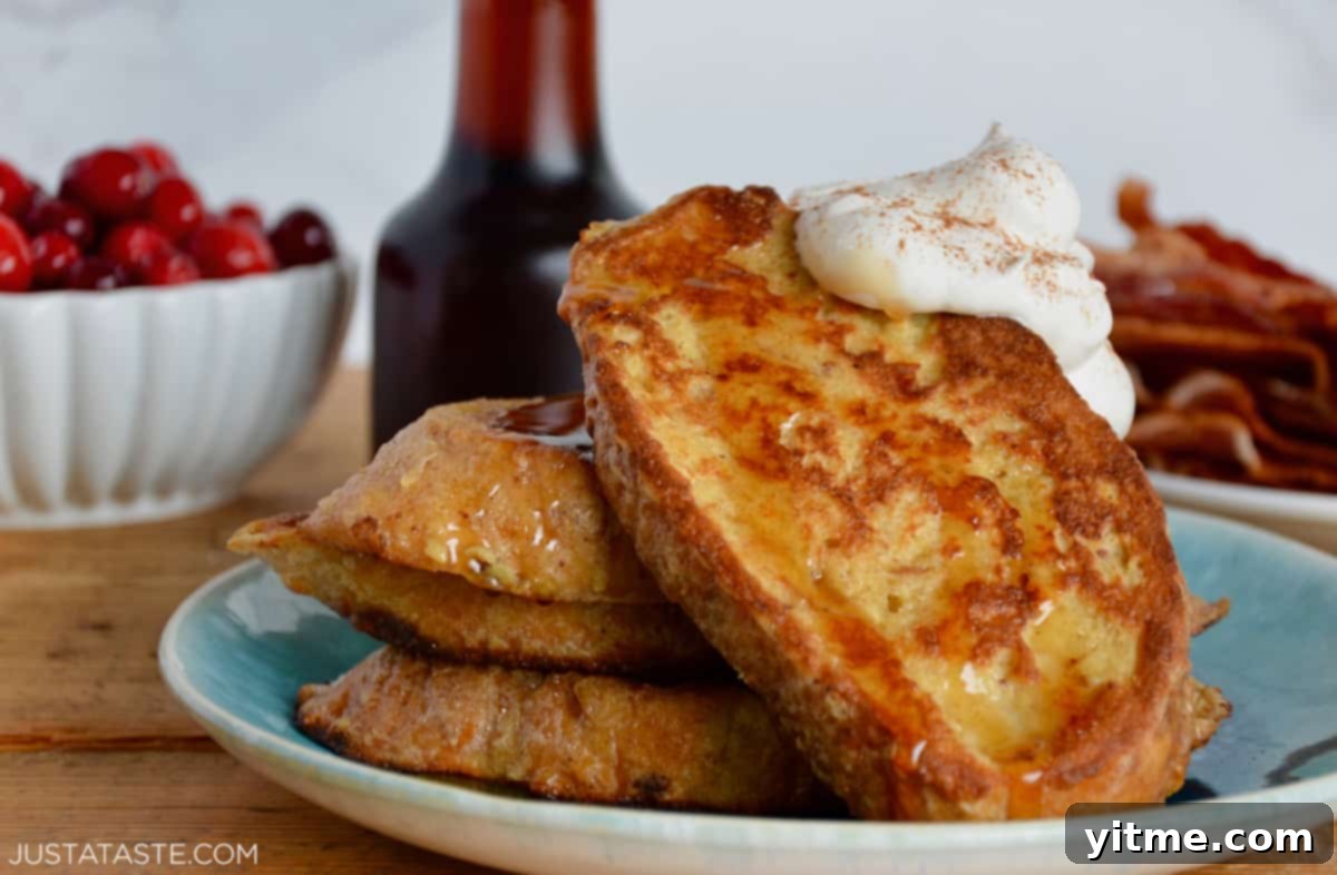 French toast served with whipped cream, maple syrup, bacon, and cranberries.