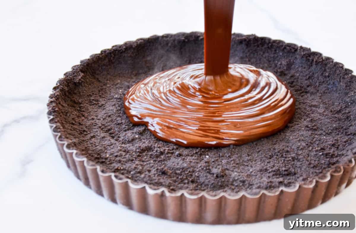 Effortless Raspberry Chocolate Tart 4 Chocolate ganache being carefully poured into a prepared Oreo cookie tart crust.