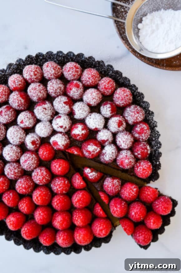 Effortless Raspberry Chocolate Tart 9 Top-down view of Easy No-Bake Chocolate Tart with Raspberries half dusted with powdered sugar
