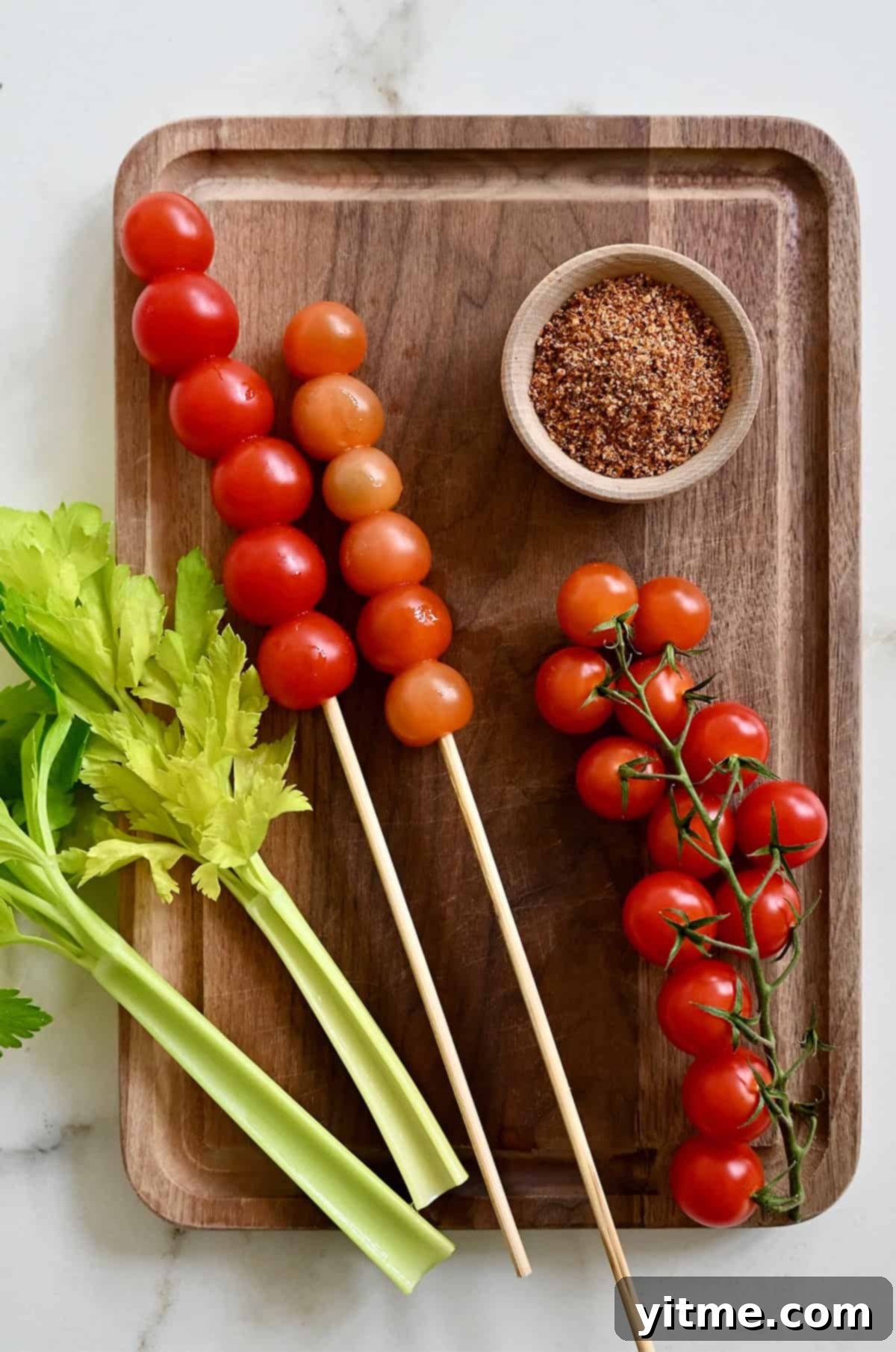 Bloody Mary Pitchers 5 Bloody Mary garnishes: celery stalks, cherry tomatoes on wooden skewers, and a small bowl filled with Tajin seasoning to rim glasses.