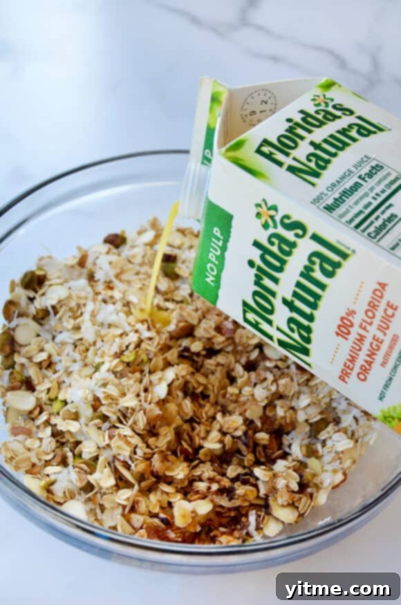 Orange-Kissed Honey Granola Parfaits 4 A carton of orange juice being poured into a bowl with granola ingredients