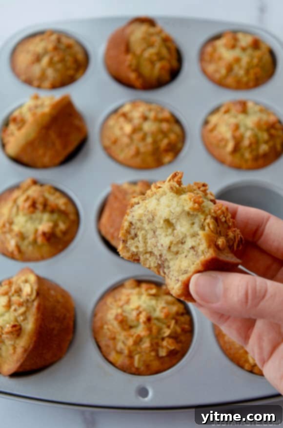 Hand holding banana muffin with bite taken out of it