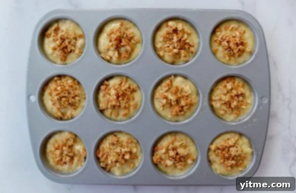Unbaked banana batter topped with granola in muffin tin