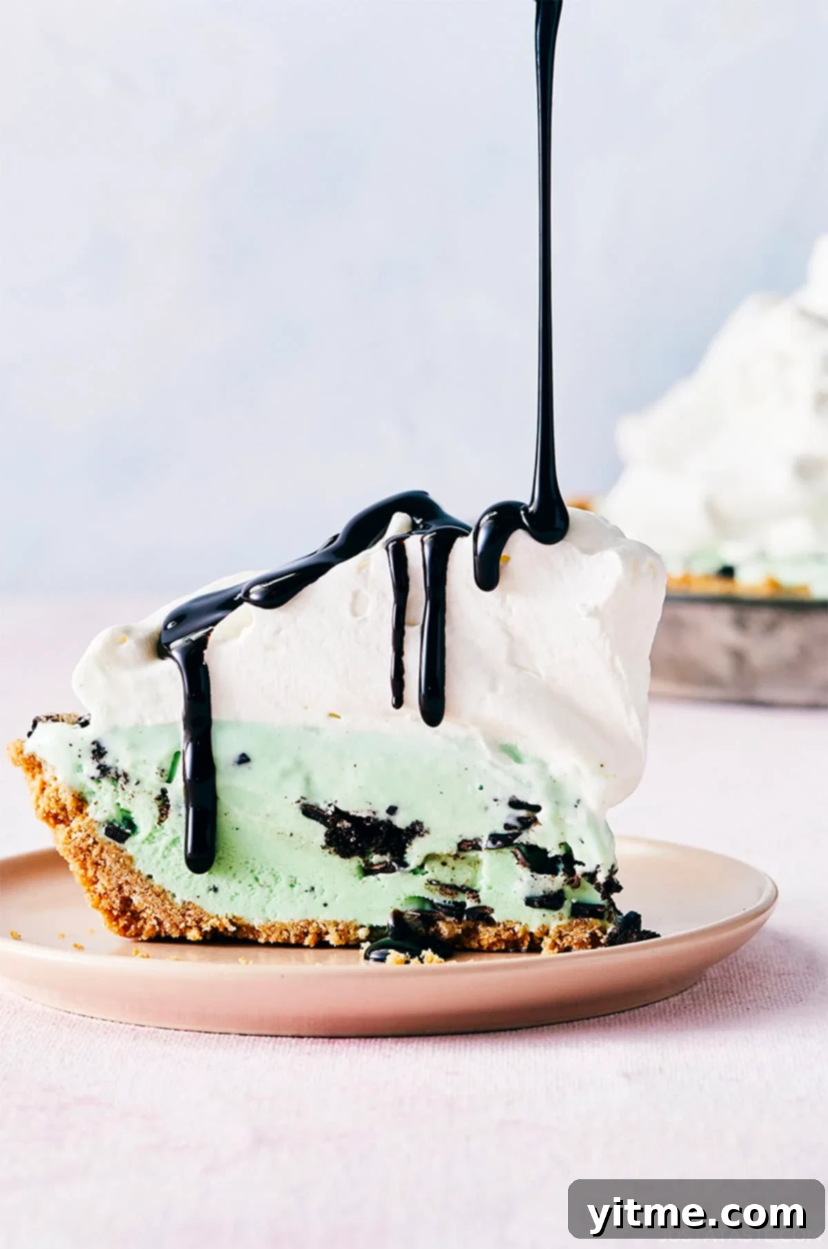 Mystery Ingredient Ice Cream Pie 2 Mint chocolate chip ice cream pie with a waffle cone crust topped with a thick layer of whipped cream and drizzled with chocolate syrup, ready to be served.