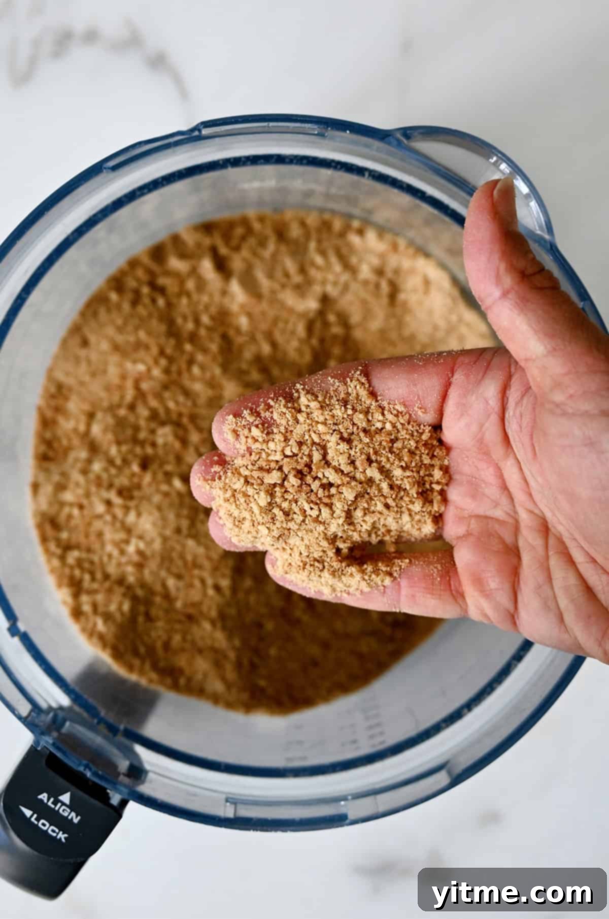 Mystery Ingredient Ice Cream Pie 6 A hand holds finely crushed waffle cones over a food processor, demonstrating the desired crumb consistency.
