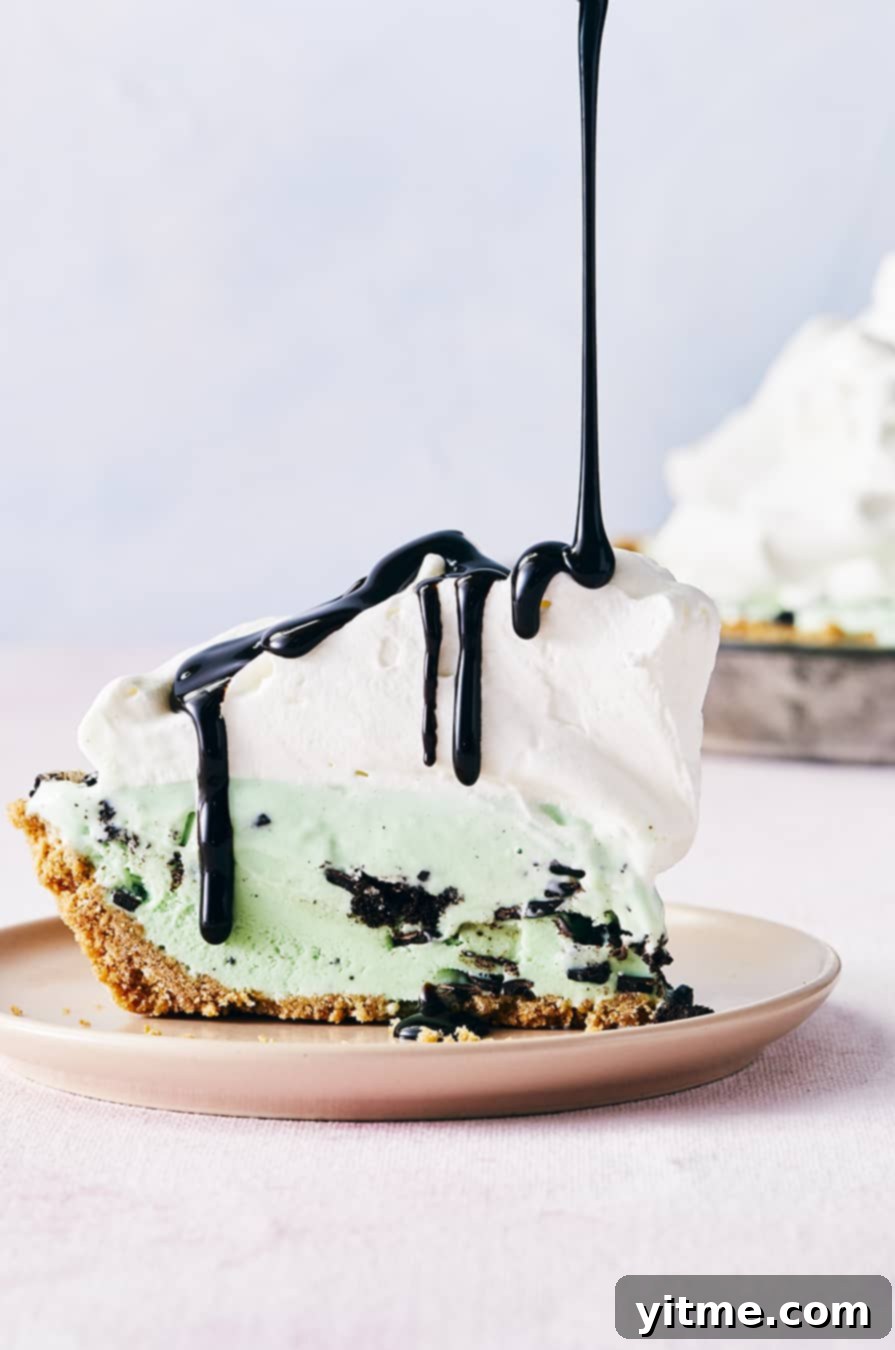 Mystery Ingredient Ice Cream Pie 10 A slice of ice cream pie topped with whipped cream with chocolate sauce drizzled on top, revealing layers of ice cream and a crispy crust.