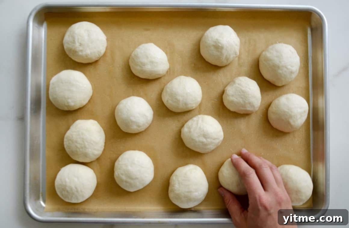 Perfectly portioned balls of pretzel dough resting on a baking sheet, ready for their crucial baking soda bath.