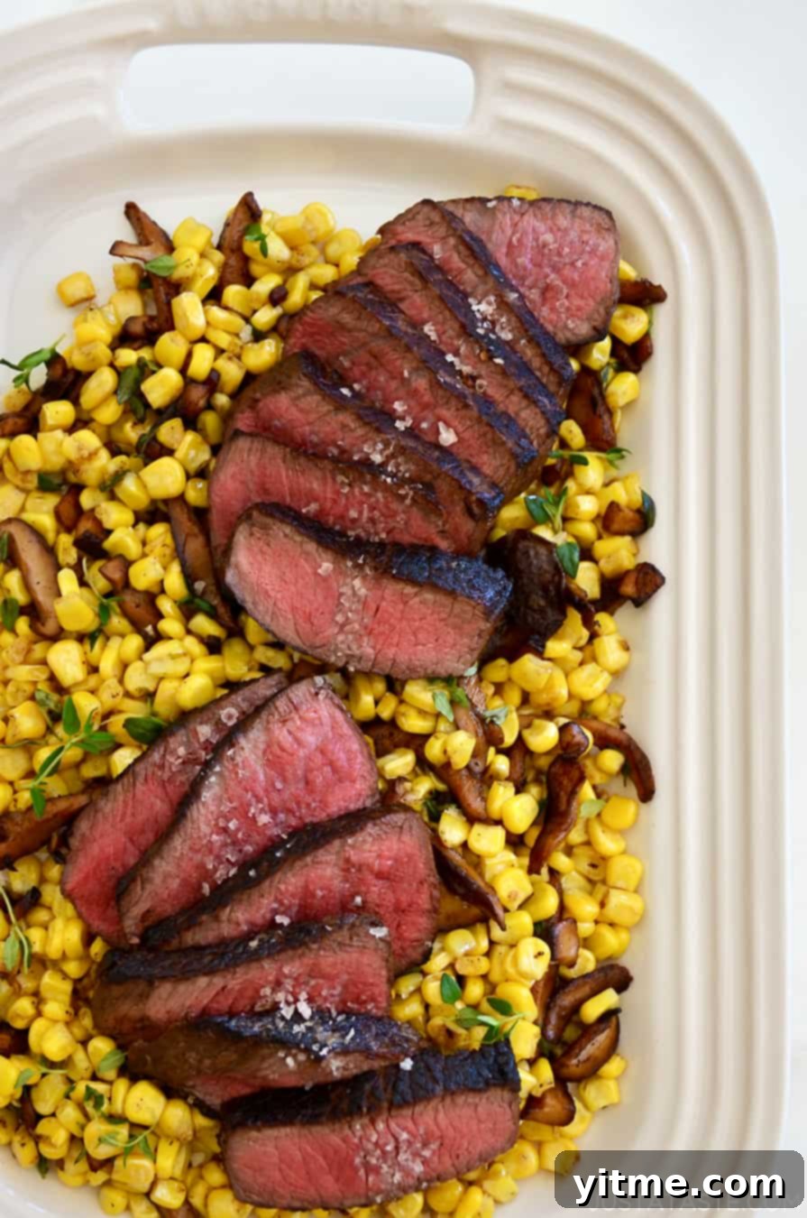 Perfectly cooked steak slices on a white platter with corn and mushrooms