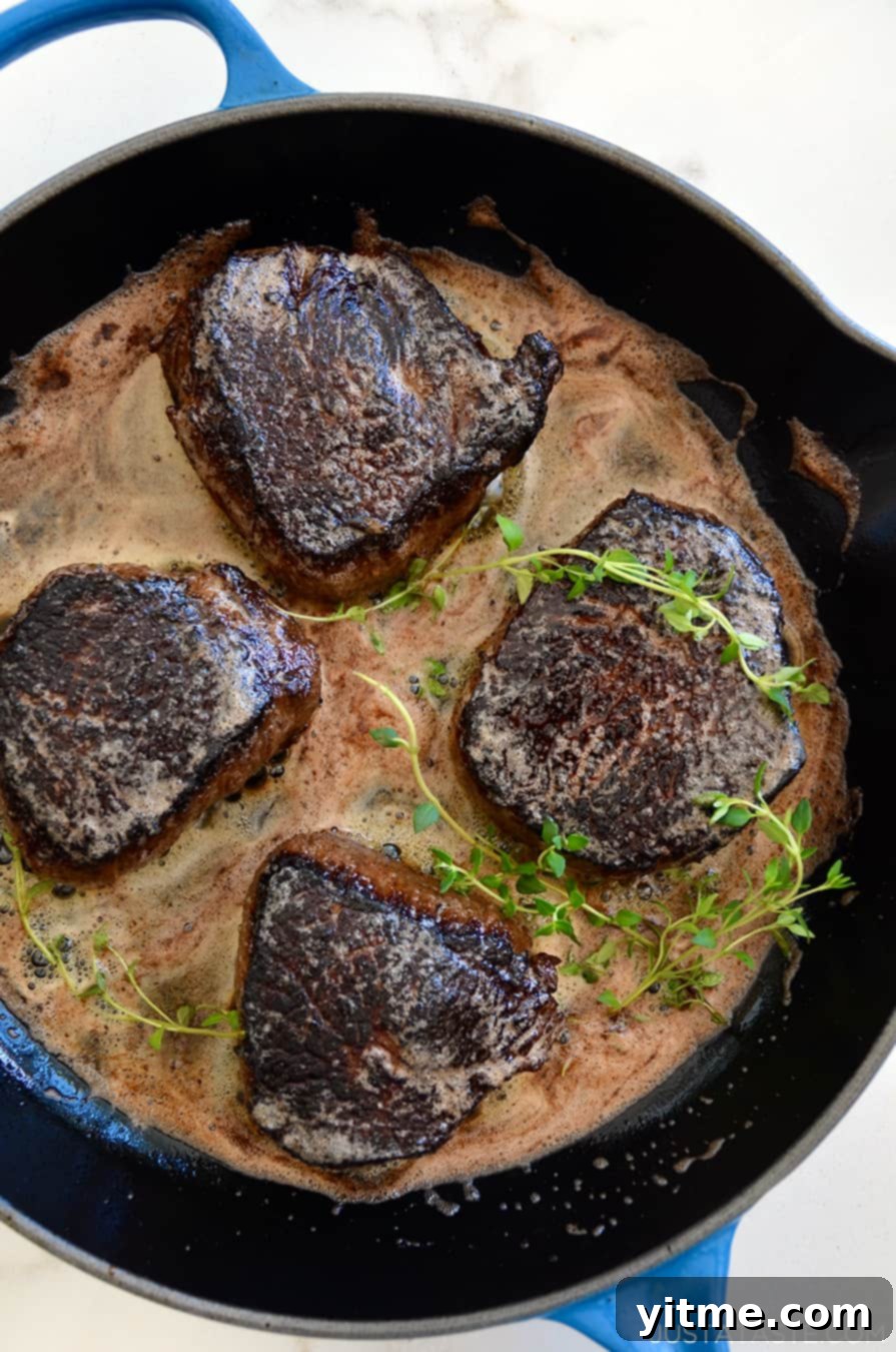 Juicy steaks sizzling in a blue skillet with thyme and butter