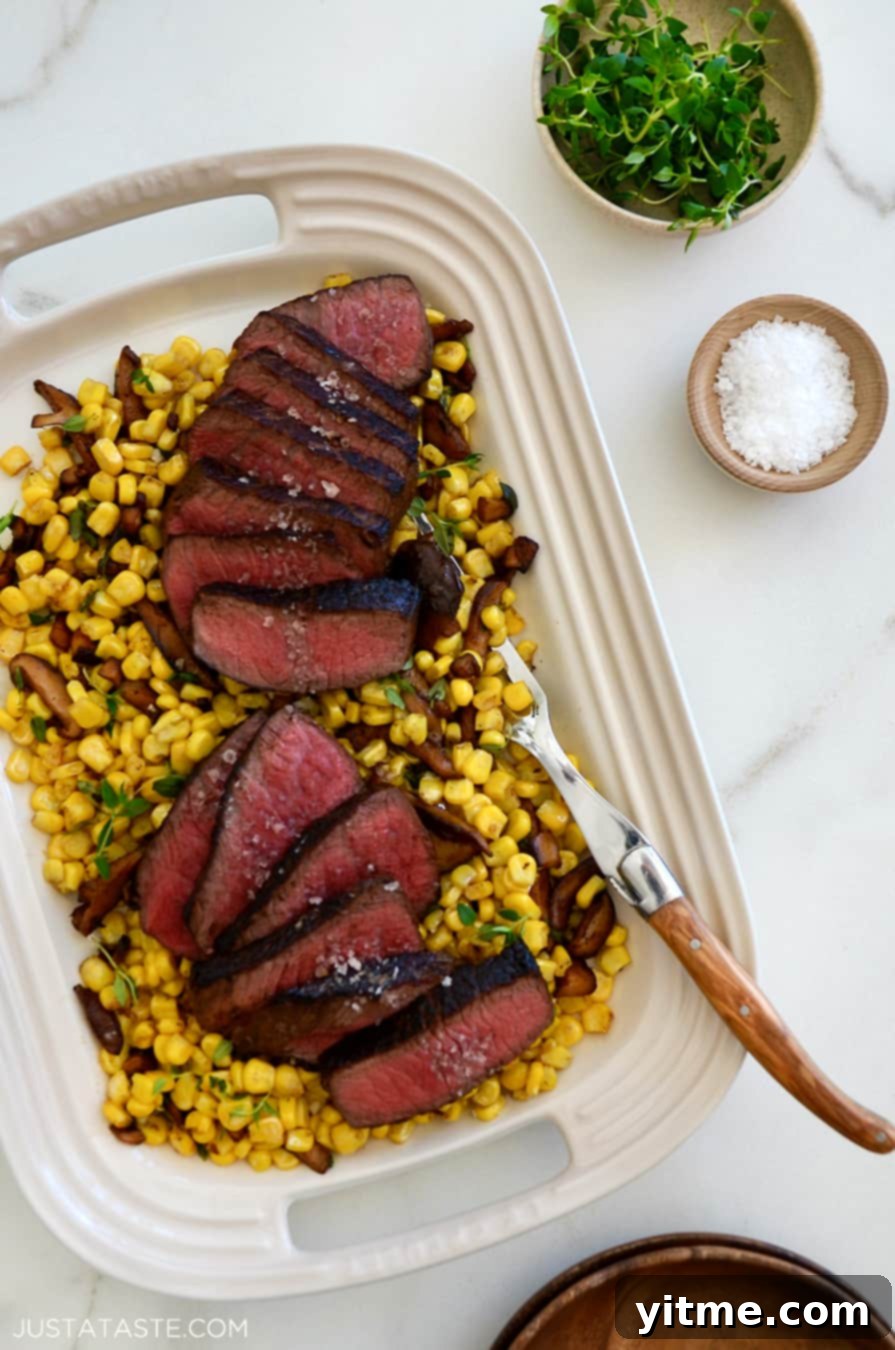 A perfectly cooked steak and corn plated with thyme