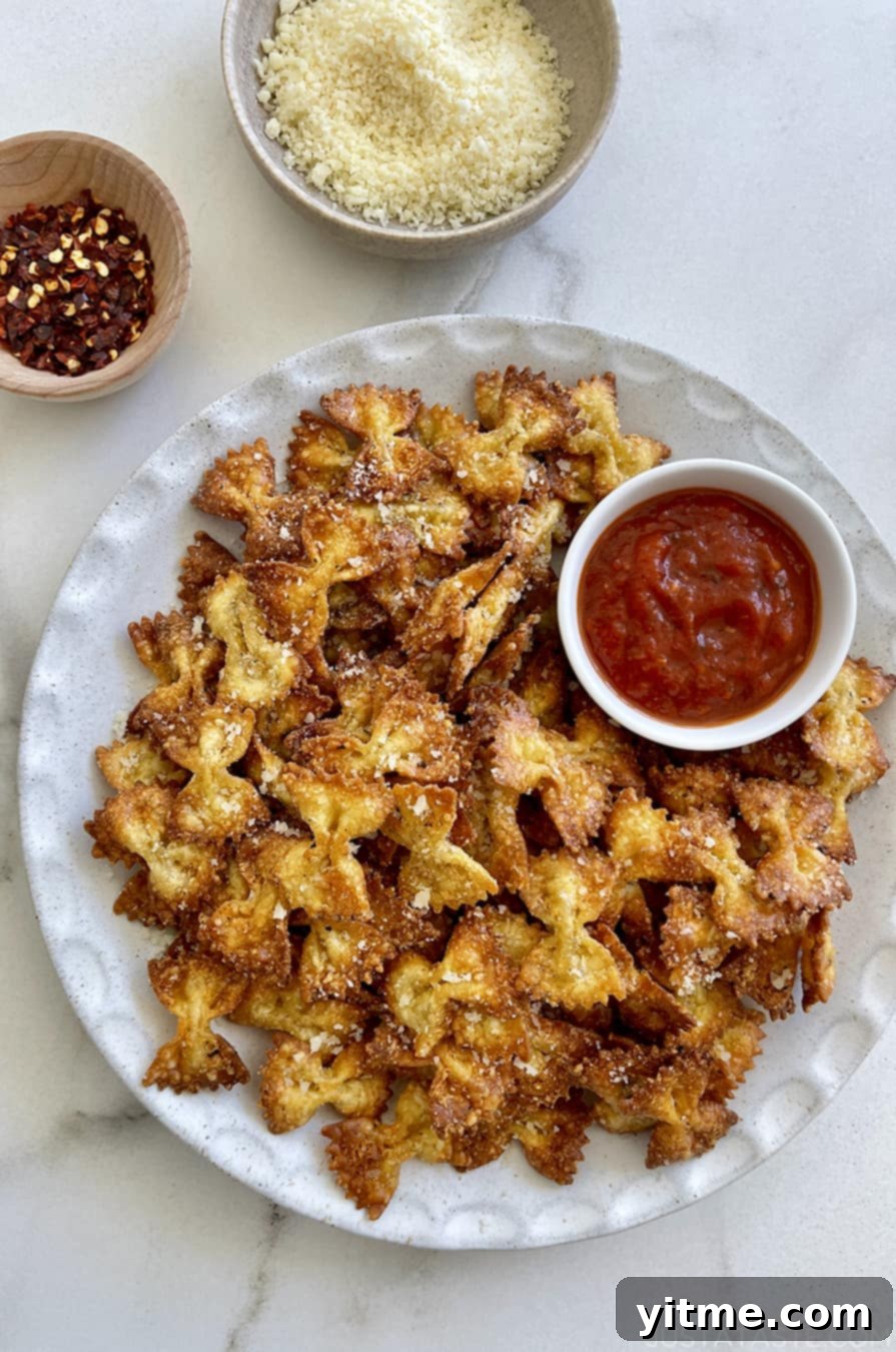 A plate of Parmesan pasta chips served with marinara sauce, highlighting their golden-brown crispiness