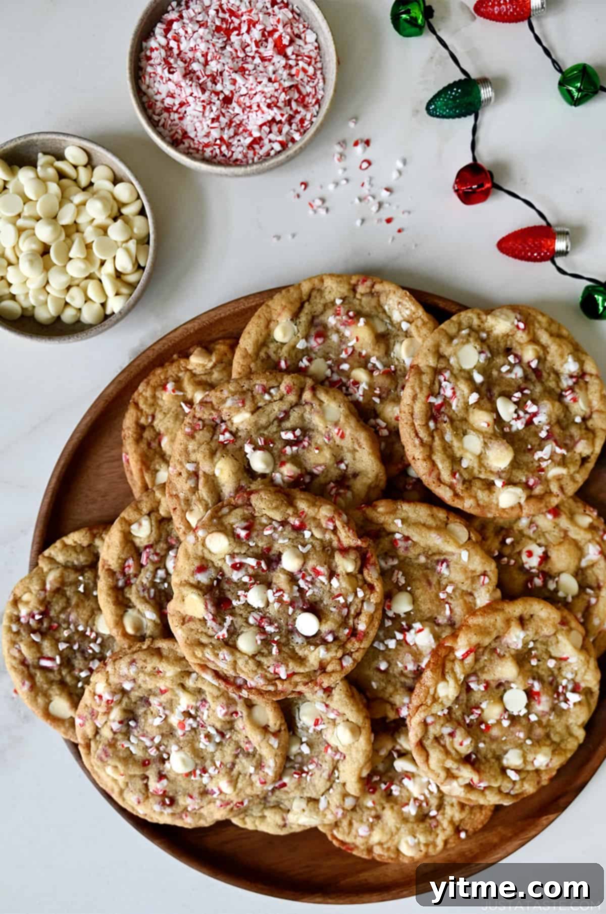 White chocolate peppermint cookies artfully arranged on a festive platter, with small bowls of white chocolate chips and crushed candy canes nearby, setting a perfect holiday scene.