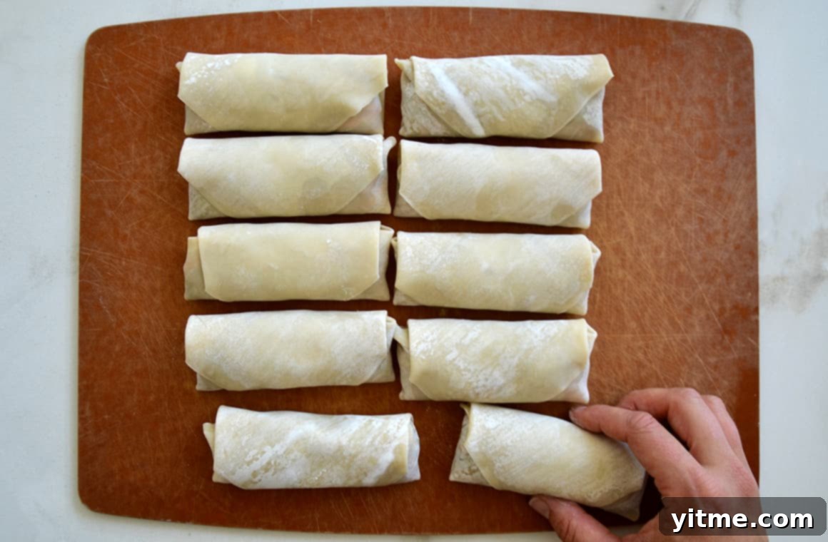 Two rows of perfectly formed egg rolls, ready to be air fried to golden perfection