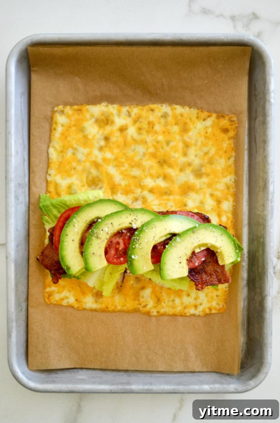 Cheesy Keto Wraps 2 A top-down view of melted cheese sandwich wrap filled with turkey, bacon, avocado, lettuce and tomato
