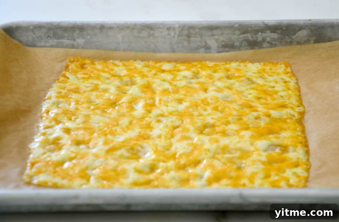 Cheesy Keto Wraps 4 Melted cheese on parchment paper atop a baking sheet