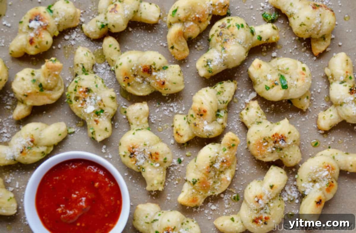 Speedy Garlic Knots: A Simple Recipe 3 Close-up shot of freshly baked garlic knots topped with Parmesan cheese and a side of marinara sauce.