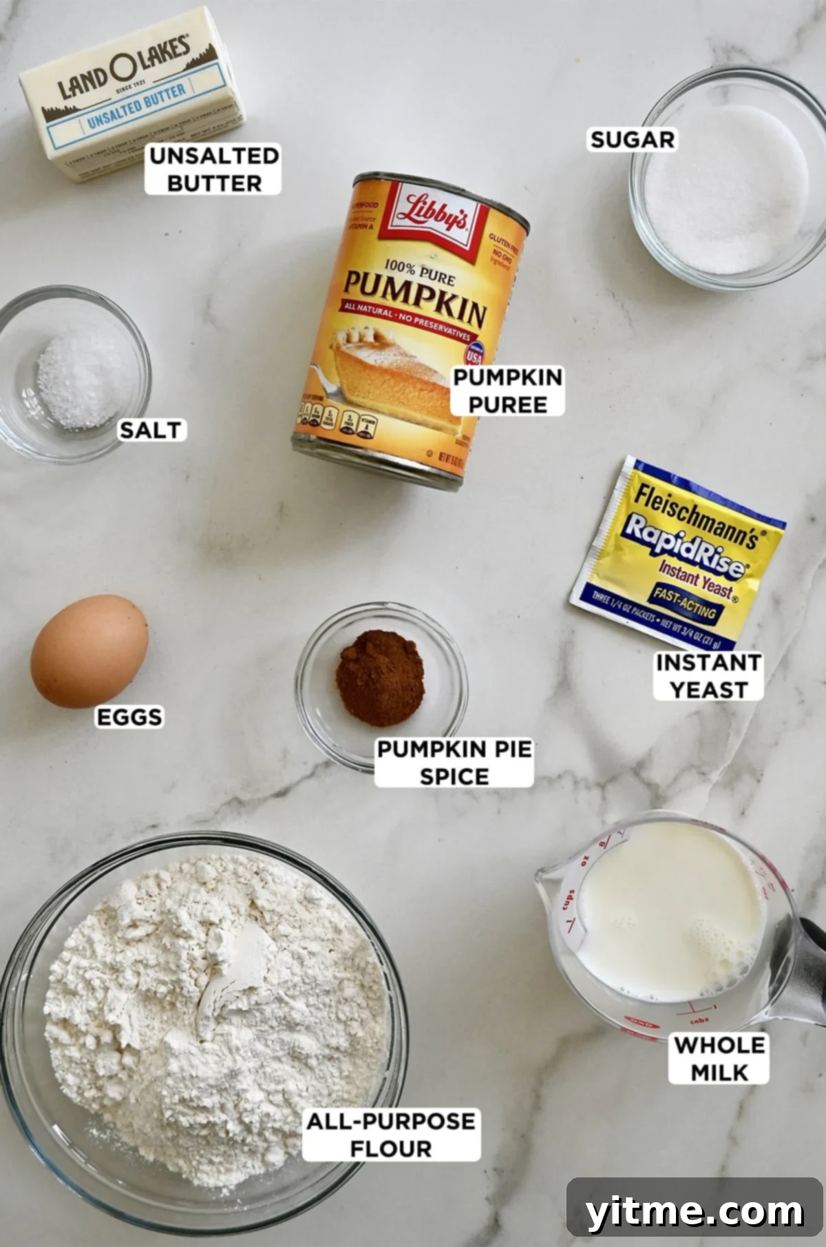 Ingredients for pumpkin dinner rolls: flour, sugar, yeast, pumpkin pie spice, egg, salt, pumpkin puree, and milk.