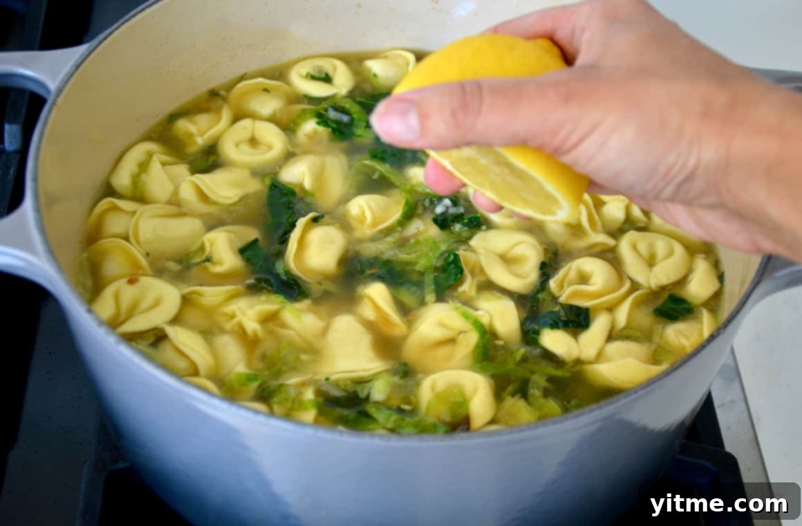 Tortellini Soup with Tuscan Kale 6 A hand squeezing lemon juice into a pot of soup.