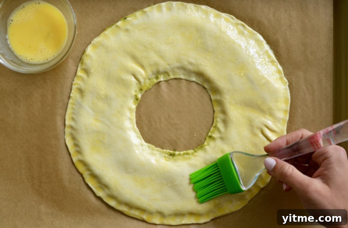Brushing egg wash on puff pastry wreath