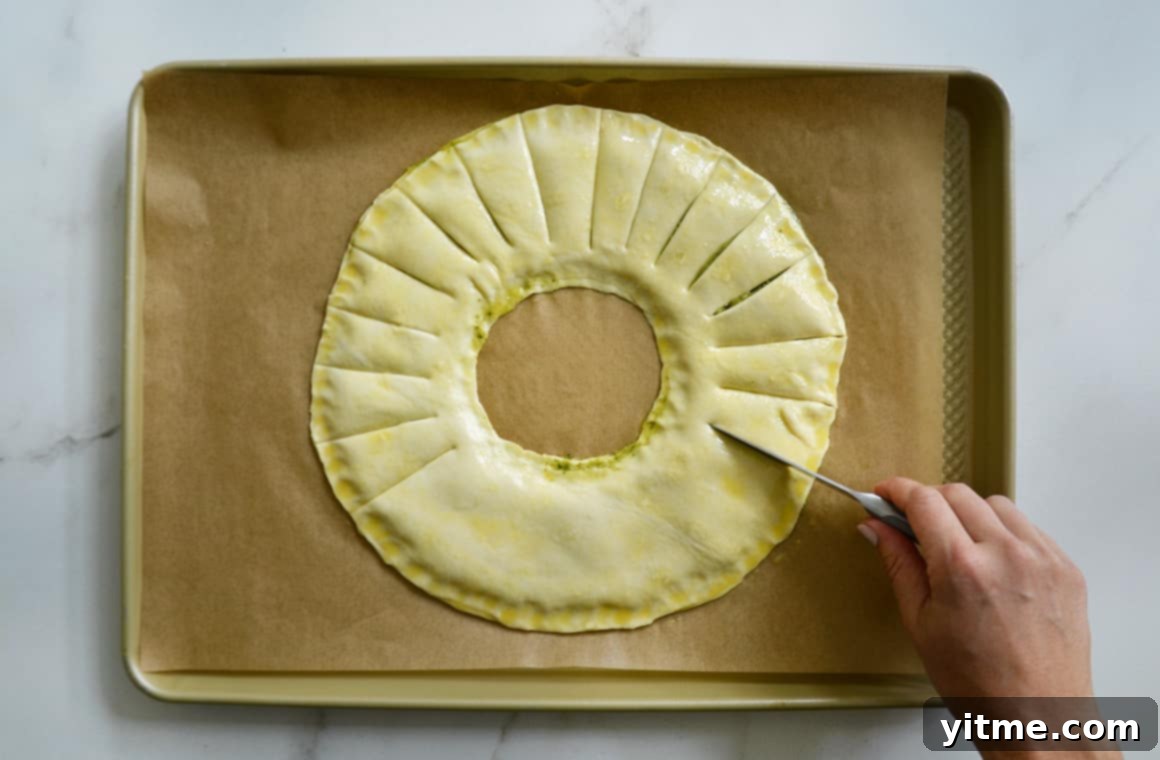 Cutting strips into the puff pastry wreath with a pizza wheel