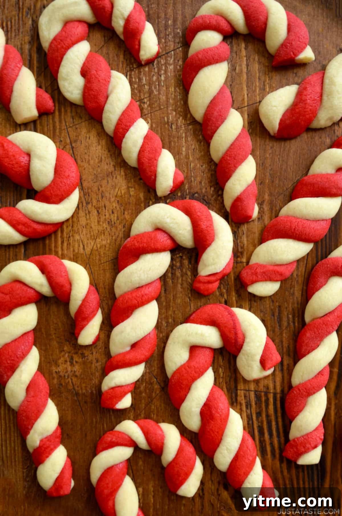 Festive candy cane cookies arranged on a wooden surface, showcasing their delightful red and white swirls.