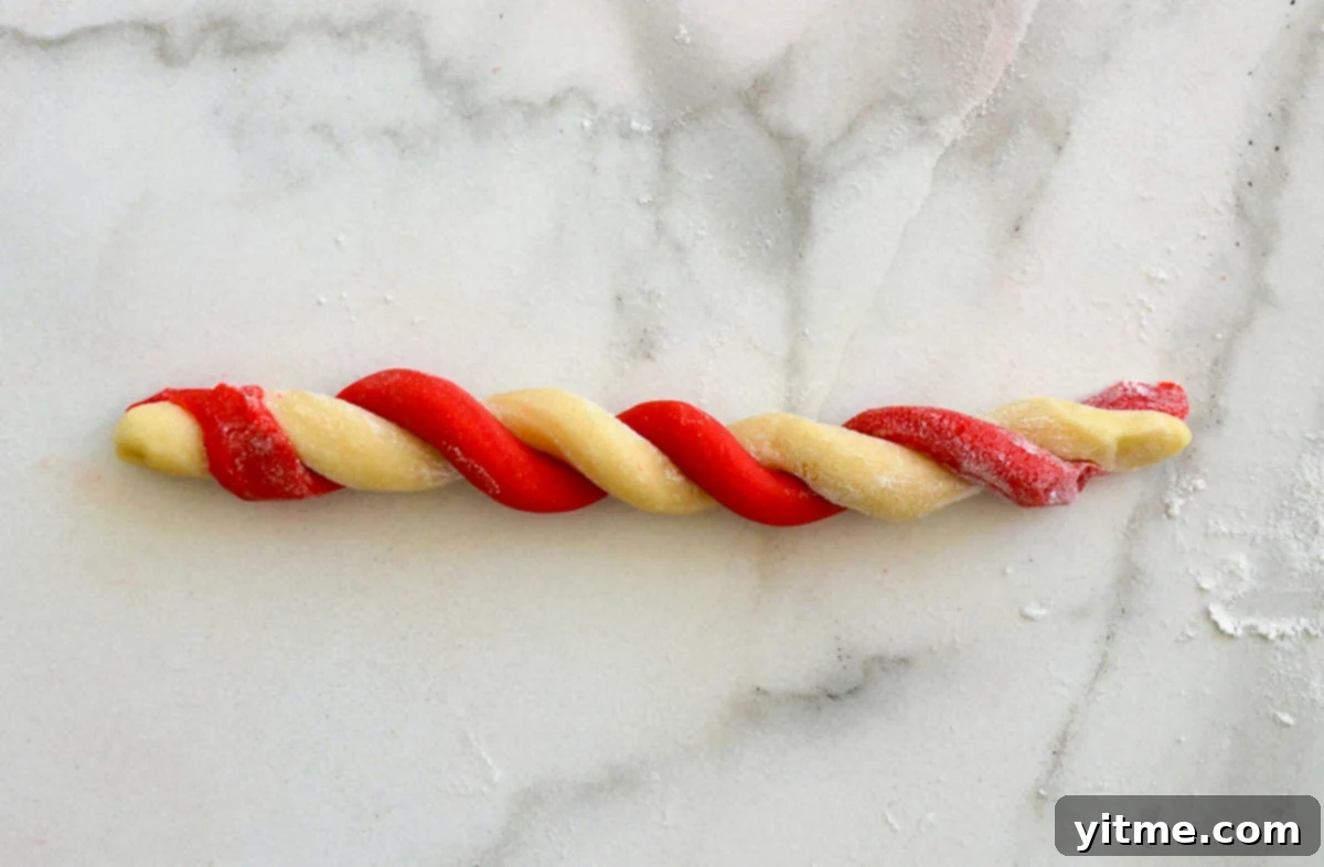 A red cookie dough log twisted together with a plain cookie dough log.