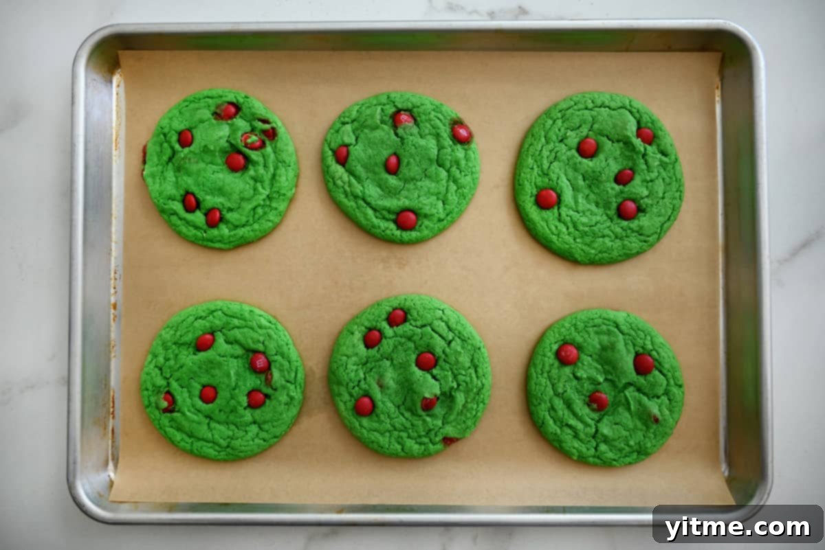 Baked Grinch cake mix cookies are on a parchment-lined baking sheet.