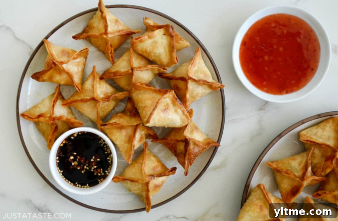 Creamy Air Fryer Wonton Bites 5 A plate filled with Air Fryer Cream Cheese Wontons alongside dipping sauces.