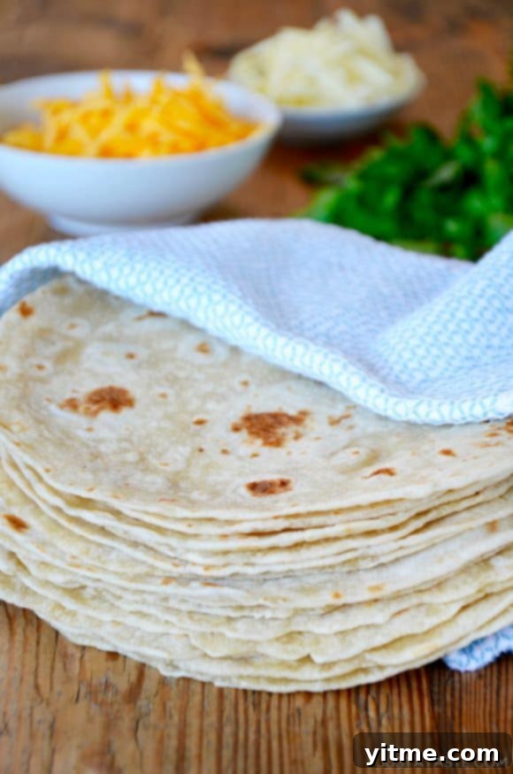 Top Recipes That Defined 2021 5 A stack of homemade tortillas in a blue towel with cheese and cilantro in the background