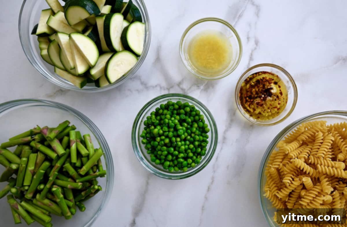 Ingredients for Pasta Primavera including pasta, zucchini, peas, asparagus, Parmesan, garlic, and oil.