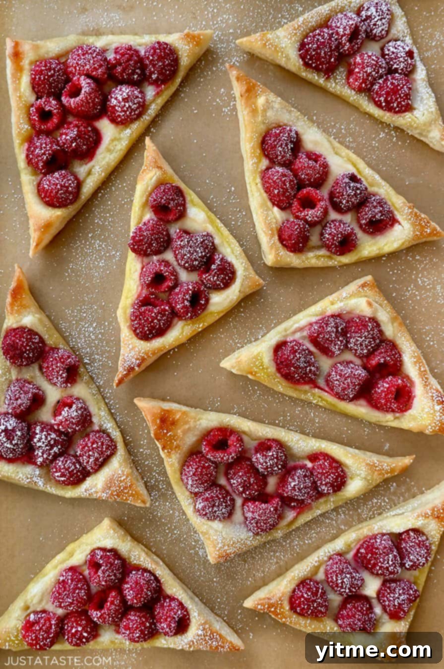 Raspberry Cream Cheese Danish 2 A top-down view of Raspberry Cream Cheese Danish dusted with powdered sugar atop brown parchment paper