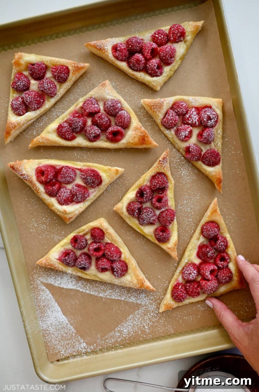 Raspberry Cream Cheese Danish 3 A hand reaches for a raspberry and cream cheese danish
